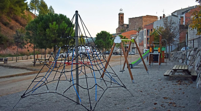 Una piràmide de cordes en primer pla , seguit d'uns gronxadors pels infants al Poble Vell. Al fons, el campanar de l'Església del Roser i el Castell. .